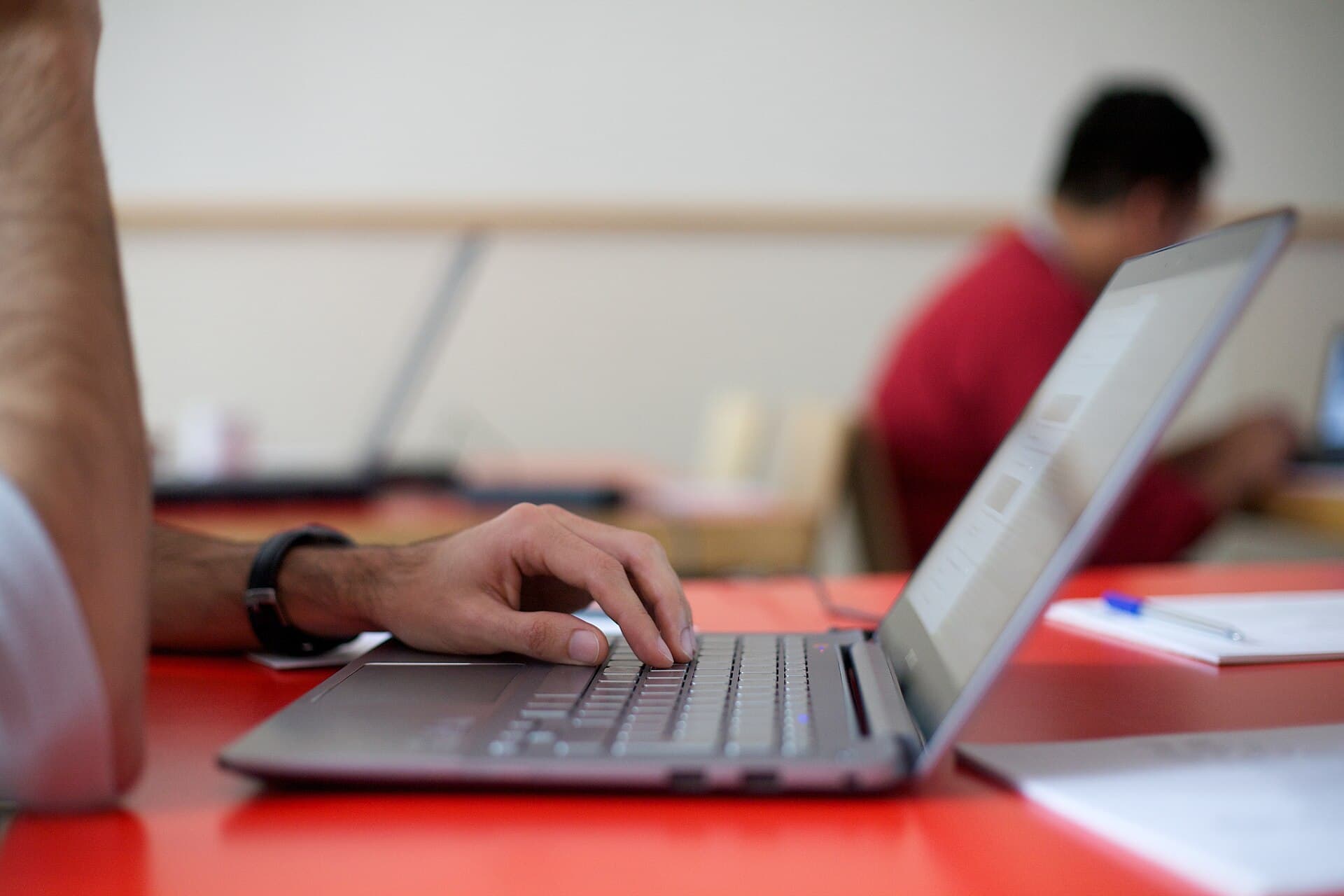 Više developera radi na prijenosnicima za dugim stolovima u prostoriji za hackathon